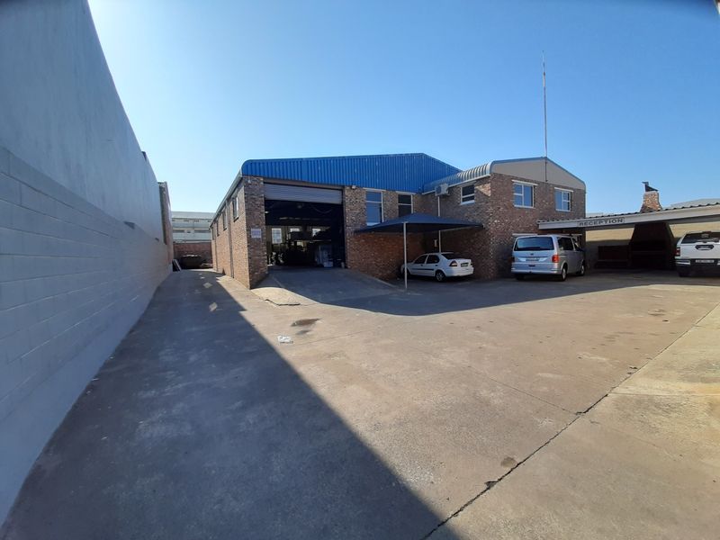 Commercial property exterior featuring a brick facade, metal roofing, concrete driveway, and a dedicated reception entrance with carport parking.