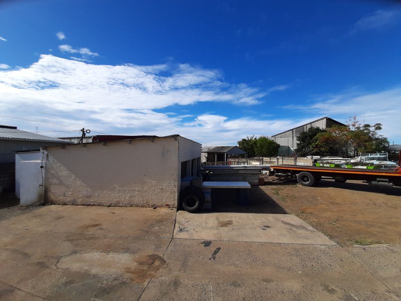 Rear industrial yard area featuring a concrete surface and a single-story outbuilding structure.