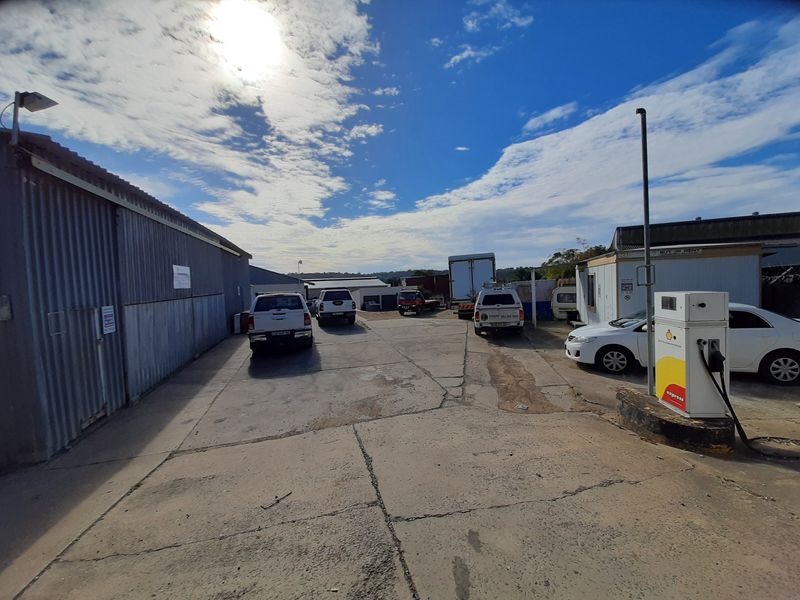 Industrial yard area featuring a concrete hardstand, corrugated metal building facade, and an on-site fuel pump station.