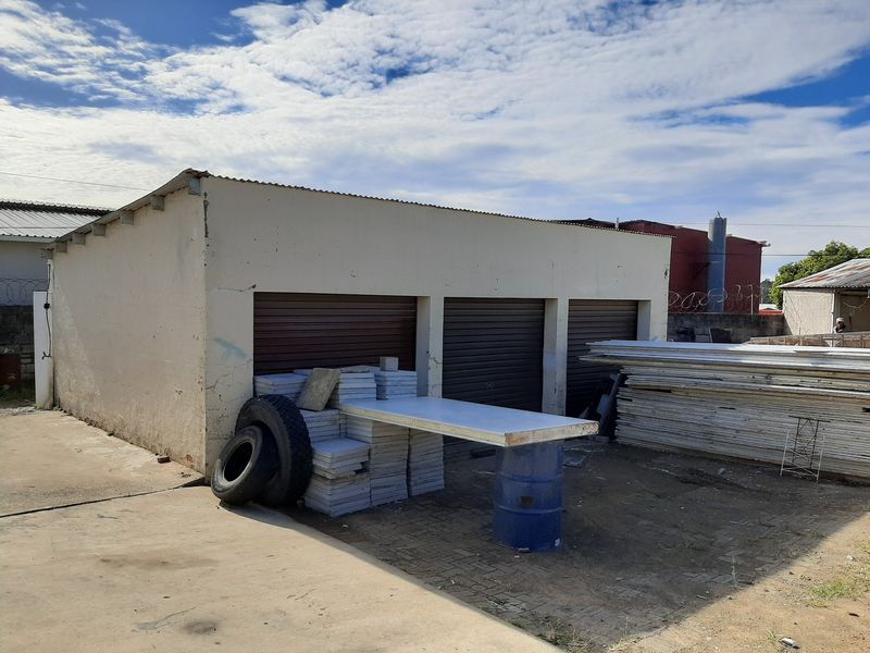 Industrial property featuring a triple garage unit with roller shutter doors, set within a paved yard area.