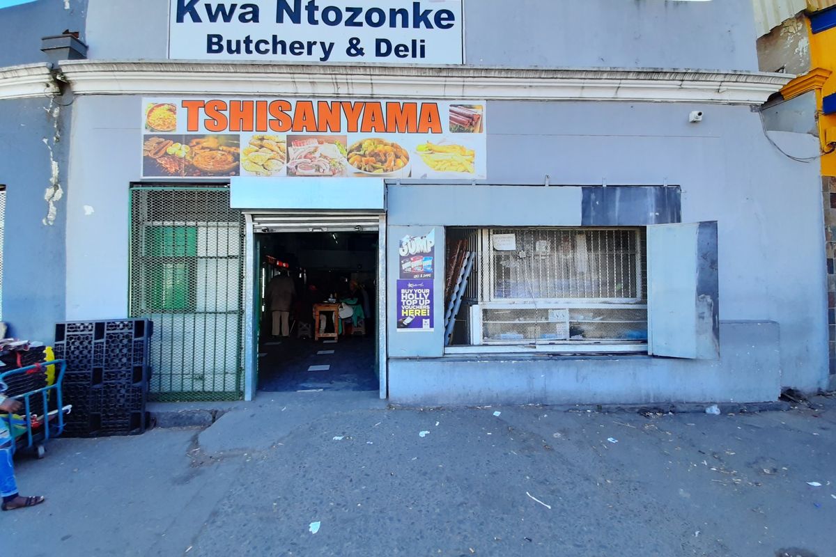 Front facade of a commercial butchery and deli featuring a service window, security gate, and prominent signage.
