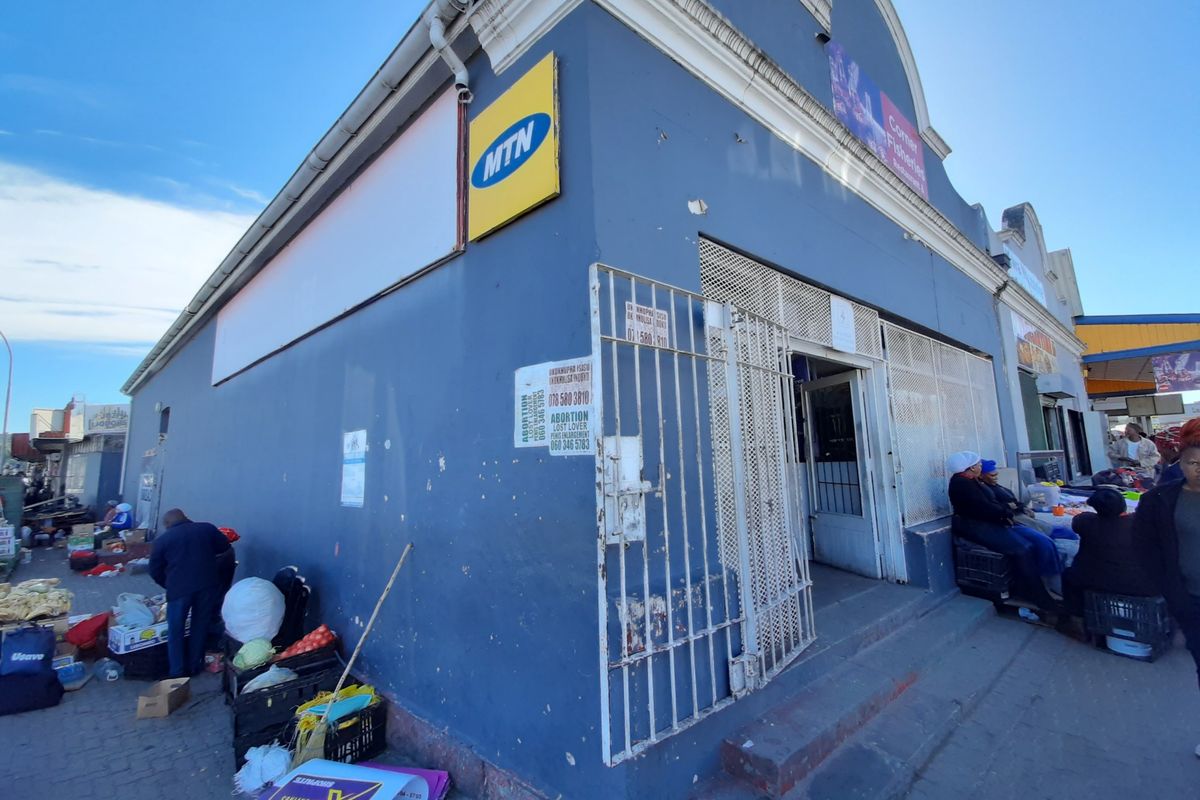 Commercial street-front property featuring a blue facade, security gates, and prominent signage in a high-traffic urban retail area.