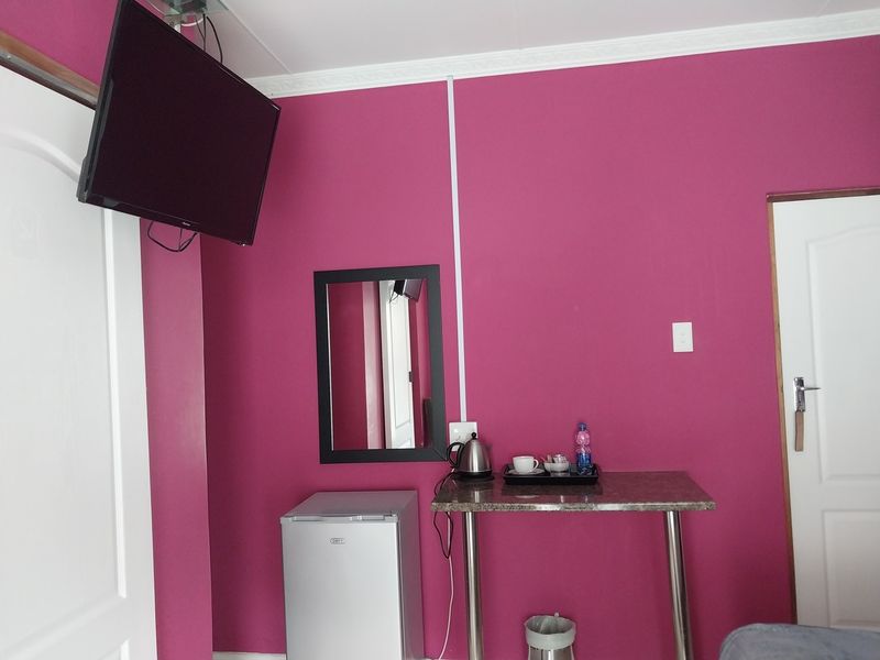 A bedroom interior featuring bold pink walls, crown molding, and functional built-in electrical infrastructure.