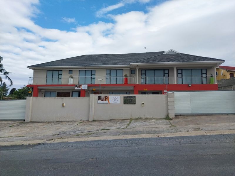 Front elevation of a two-story guest house featuring a balcony, sliding glass doors, and a secure perimeter wall with electric fencing.