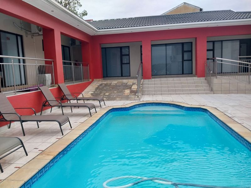 Outdoor pool area featuring a tiled deck, stainless steel railings, and access to guest house units via stairs and a ramp.