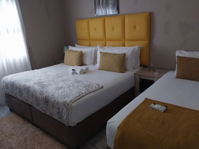 A guest bedroom featuring tiled flooring and neutral wall tones, currently furnished with a double bed and a single bed.