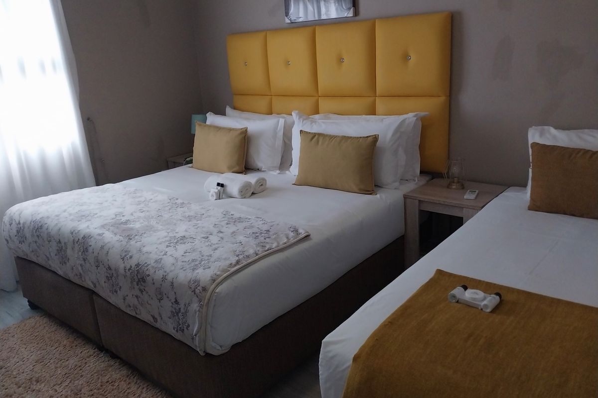 A guest bedroom featuring tiled flooring and neutral wall tones, currently furnished with a double bed and a single bed.