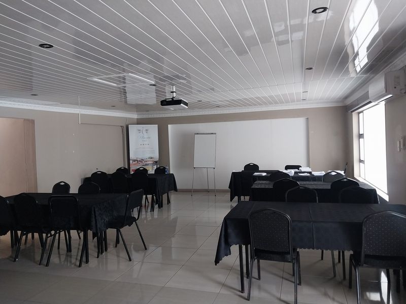 A functional conference or meeting room featuring tiled flooring, a glossy panelled ceiling with recessed lighting, and integrated climate control.