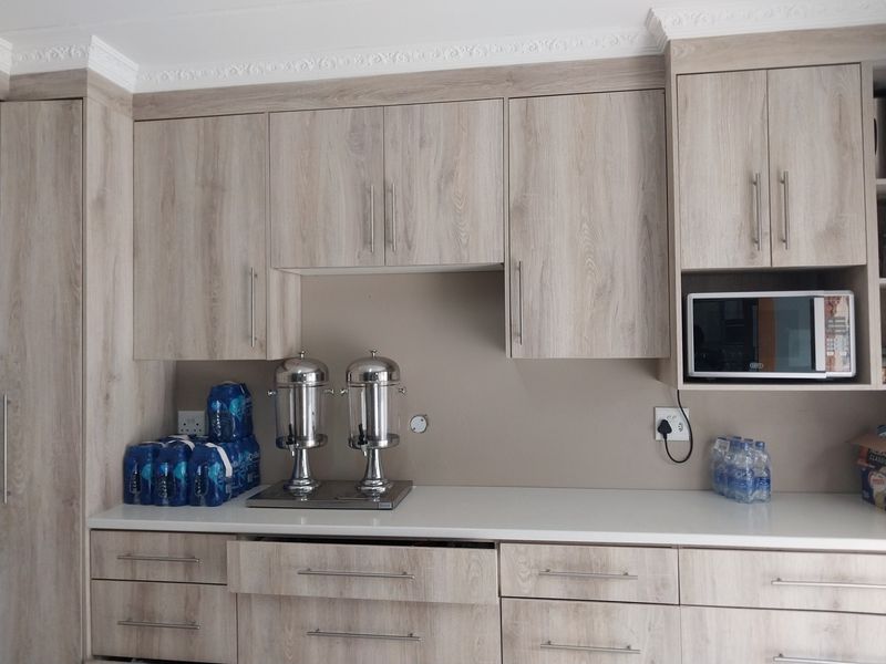 A well-maintained kitchen area featuring light wood-look cabinetry, white countertops, and a built-in microwave with decorative crown molding.