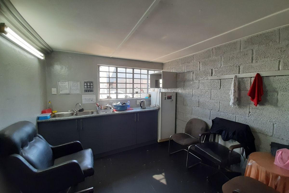 A functional kitchenette area featuring a double sink, built-in cabinetry, and exposed concrete block walls, suitable for a staff breakroom or utility space.