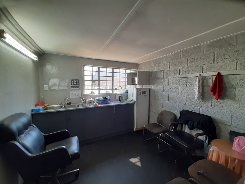 A functional kitchenette area featuring a double sink, built-in cabinetry, and exposed concrete block walls, suitable for a staff breakroom or utility space.