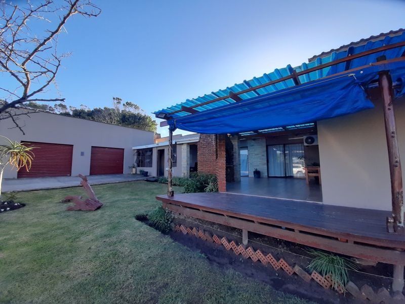 Rear view of the property featuring a timber deck, brick fireplace, and a detached garage, with a temporary tarp covering the patio area.