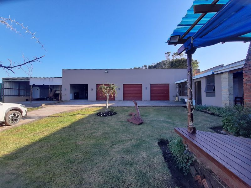 Rear view of the property featuring a triple garage, a lawn area, and a covered patio with timber decking.