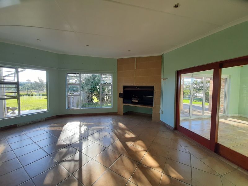 Spacious living area featuring tiled floors, a built-in fireplace, and large windows providing natural light and garden views.