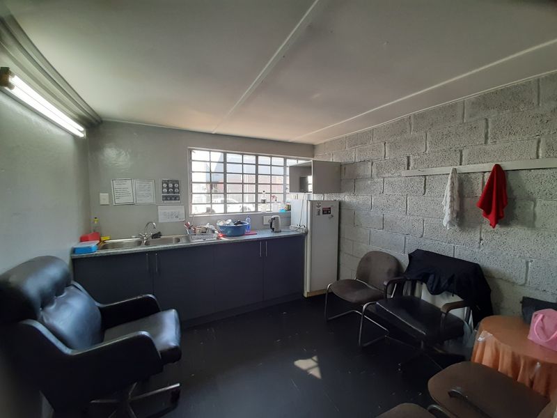 A functional kitchenette area featuring a double sink, base cabinetry, and exposed concrete block walls, suitable for a commercial breakroom or utility space.