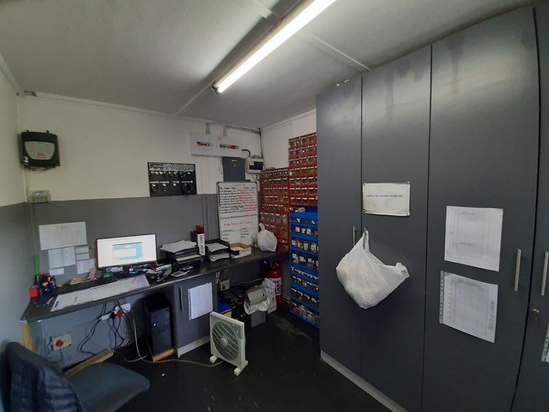 A functional utility or storage workspace featuring built-in cabinetry, a fixed workbench, and wall-mounted shelving, suitable for administrative or maintenance tasks.