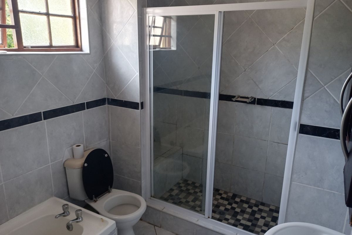 A functional bathroom featuring a shower enclosure with sliding glass doors, a standard toilet, and tiled walls with a decorative border.