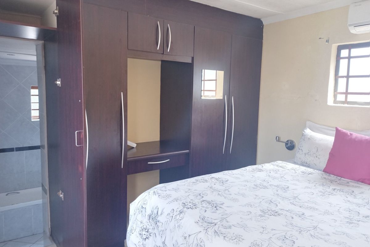 A bedroom featuring built-in dark wood cabinetry with an integrated vanity desk, tiled flooring, and an en-suite bathroom access.