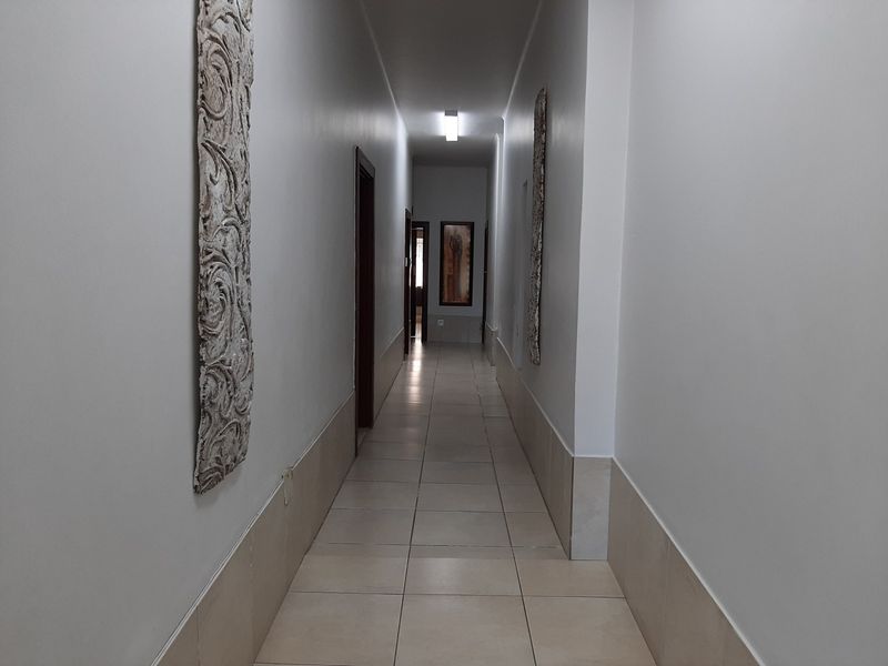 A clean, well-lit commercial hallway featuring neutral tiled flooring and multiple access points to adjacent rooms.