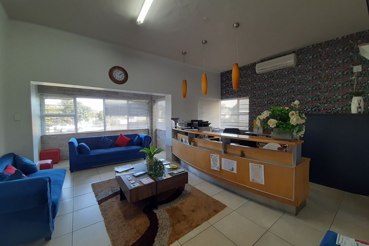 Commercial reception area featuring a built-in wooden reception desk, tiled flooring, split-system air conditioning, and decorative wallpaper.
