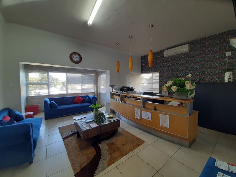 Commercial reception area featuring a built-in wooden reception desk, tiled flooring, split-system air conditioning, and decorative wallpaper.