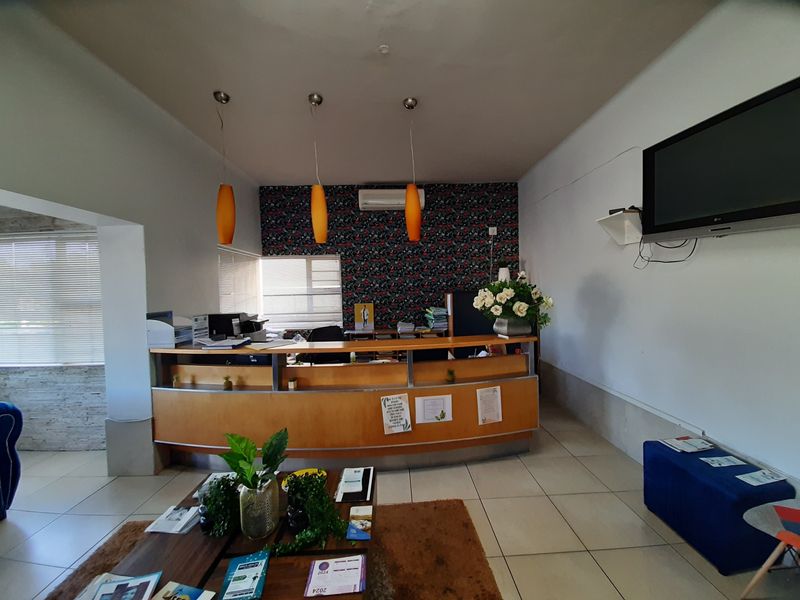 Commercial reception area featuring a built-in wooden desk, pendant lighting, split-system air conditioning, and tiled flooring.