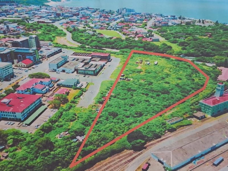 Aerial view of a large, undeveloped commercial land parcel situated within an urban environment, highlighted by a red boundary outline.