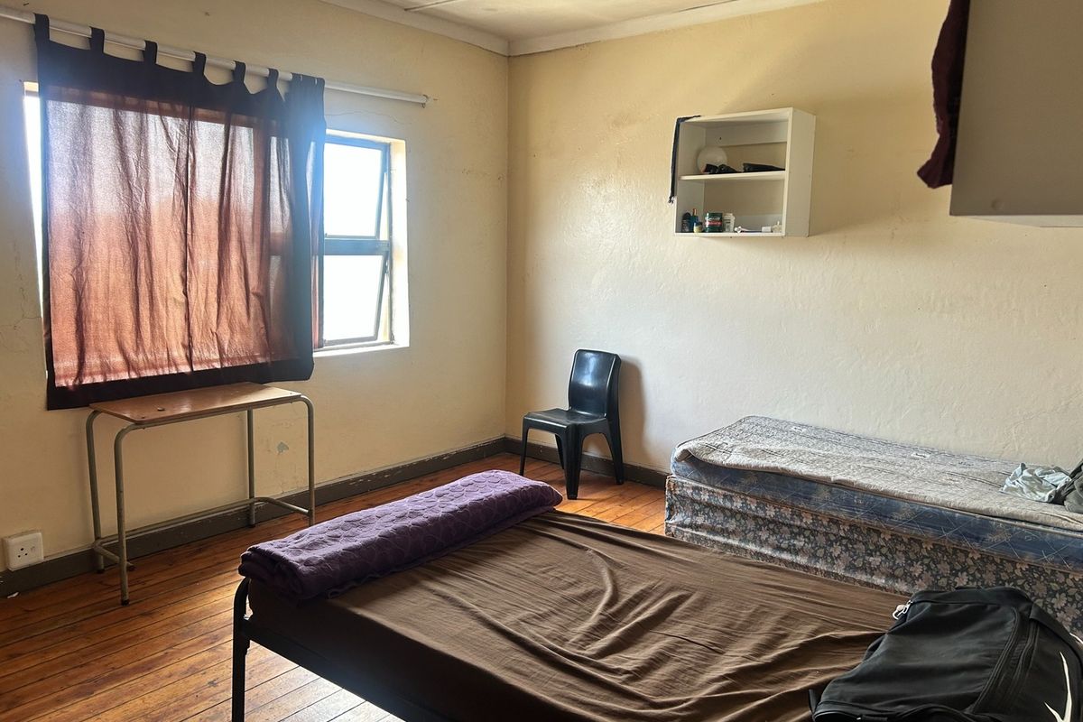 A bedroom featuring original timber flooring and a steel-framed window, requiring cosmetic updates to improve the overall condition and appeal of the space.
