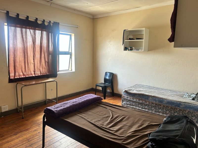A bedroom featuring original timber flooring and a steel-framed window, requiring cosmetic updates to improve the overall condition and appeal of the space.