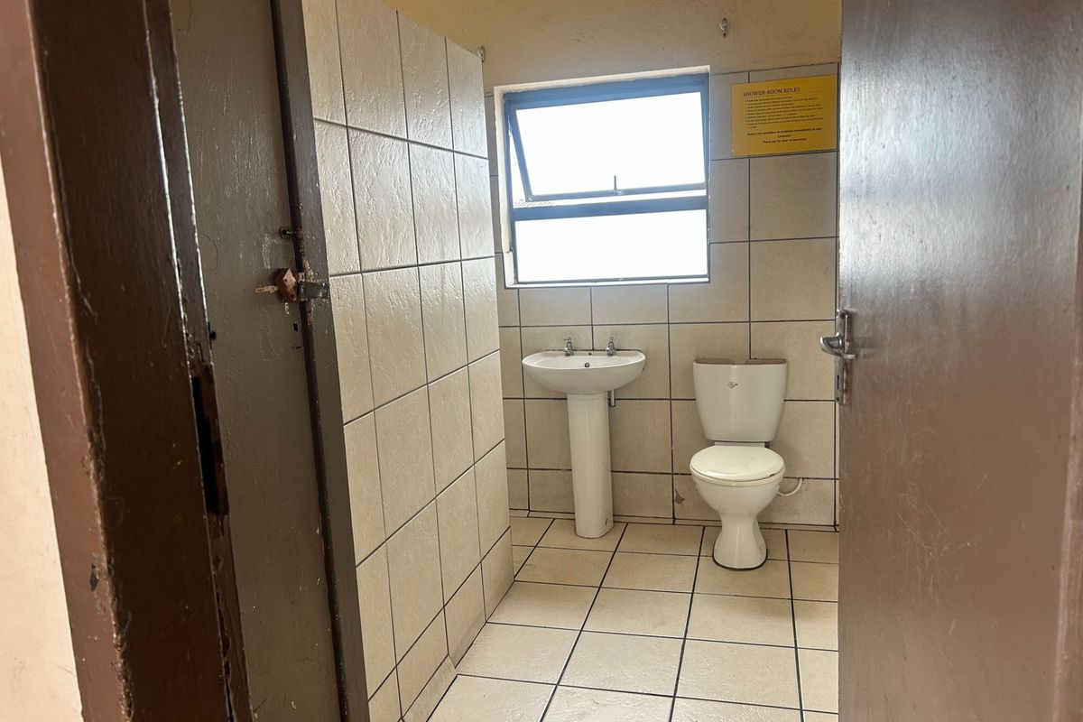 A functional bathroom featuring a pedestal basin, toilet, and tiled finishes, requiring cosmetic updates to improve its overall condition and aesthetic appeal.