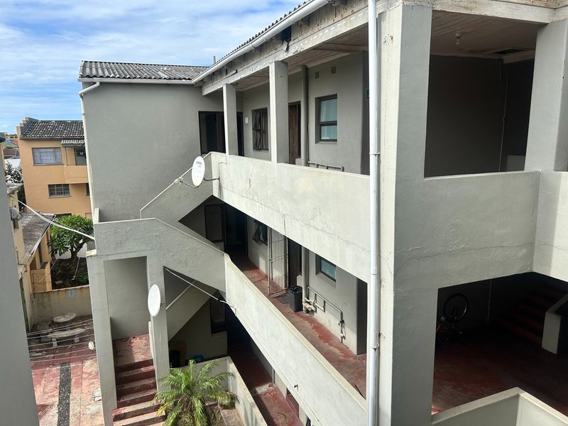 Exterior view of an apartment building showing concrete staircases, balcony walkways, and general building facade condition.