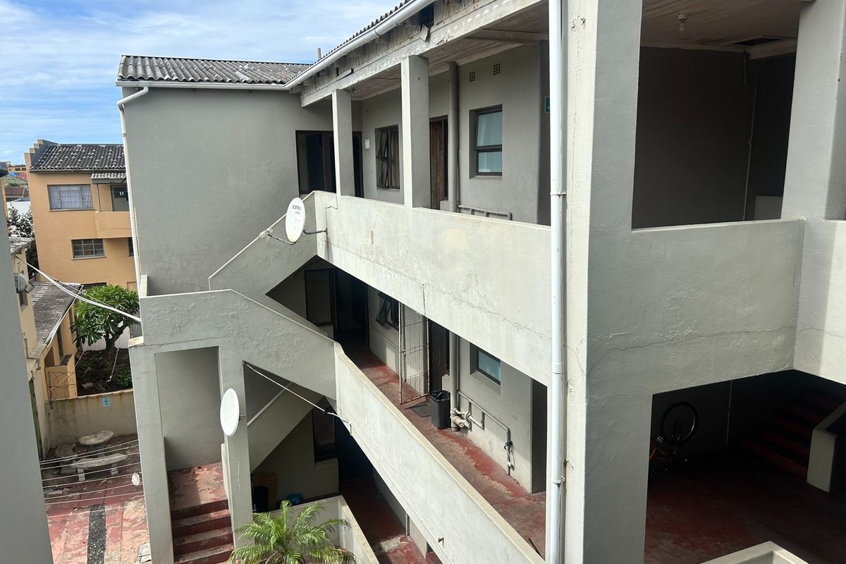 Exterior view of an apartment building showing concrete staircases, balcony walkways, and general building facade condition.