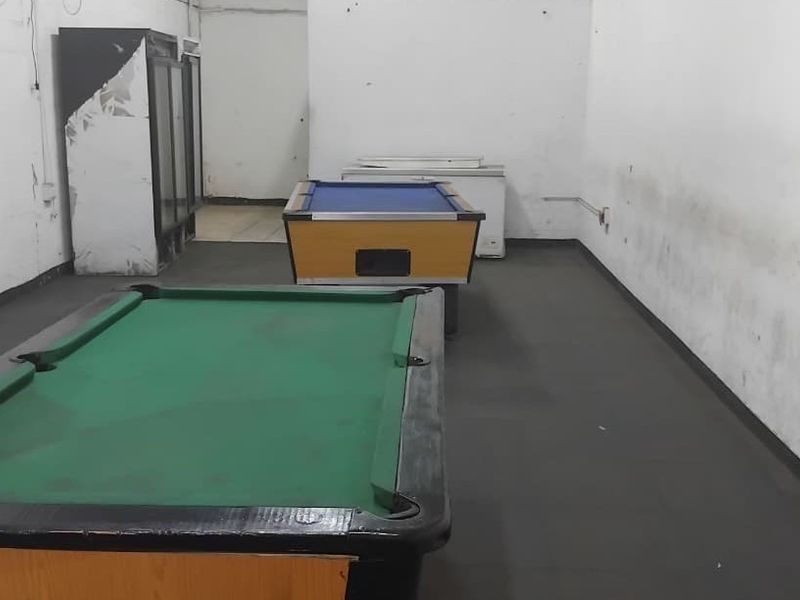 A commercial sports facility space featuring plain walls and flooring, currently utilized for recreational gaming equipment.