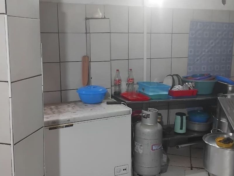 A functional kitchen area featuring tiled walls and a stainless steel sink, currently showing signs of wear and requiring maintenance.