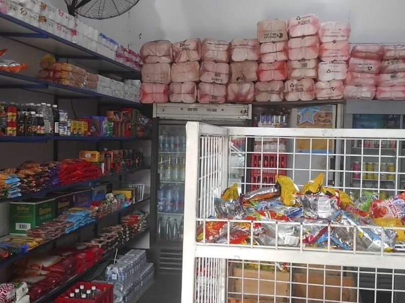 A commercial retail storage and display area featuring fixed metal shelving units and commercial refrigeration equipment for inventory management.