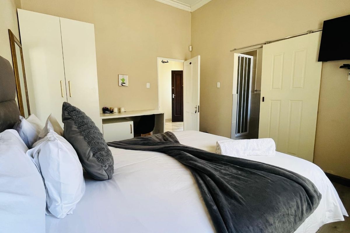 A well-maintained bedroom featuring a built-in wardrobe, integrated desk space, and a sliding door leading to an en-suite bathroom.