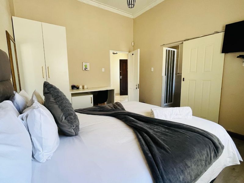 A well-maintained bedroom featuring a built-in wardrobe, integrated desk space, and a sliding door leading to an en-suite bathroom.