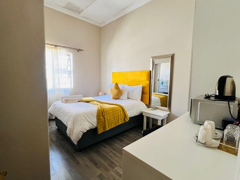 A guest bedroom featuring laminate flooring and ceiling detailing, with visible water staining on the ceiling requiring attention.