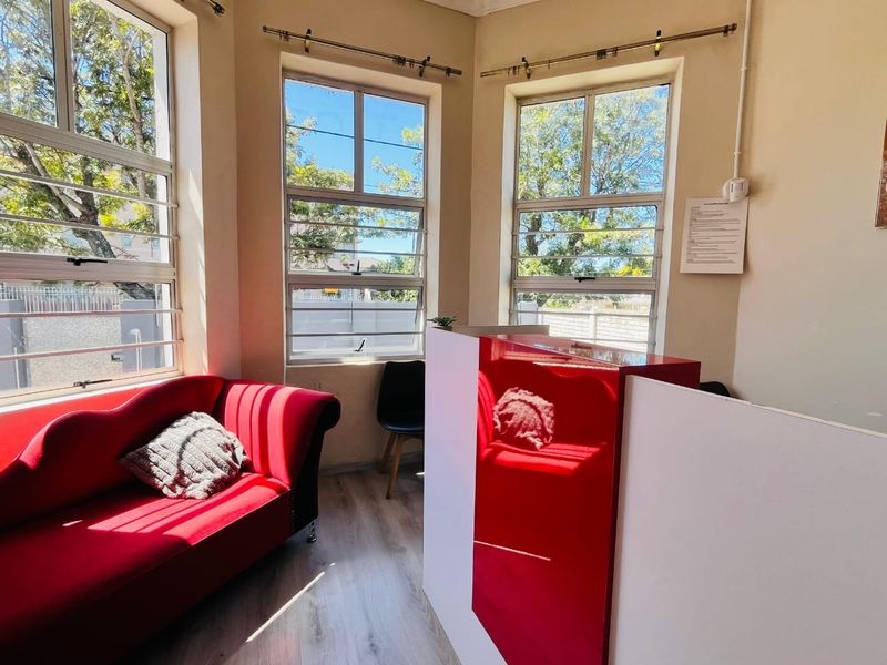 A bright reception area featuring laminate flooring, large aluminium windows, and a built-in reception desk.