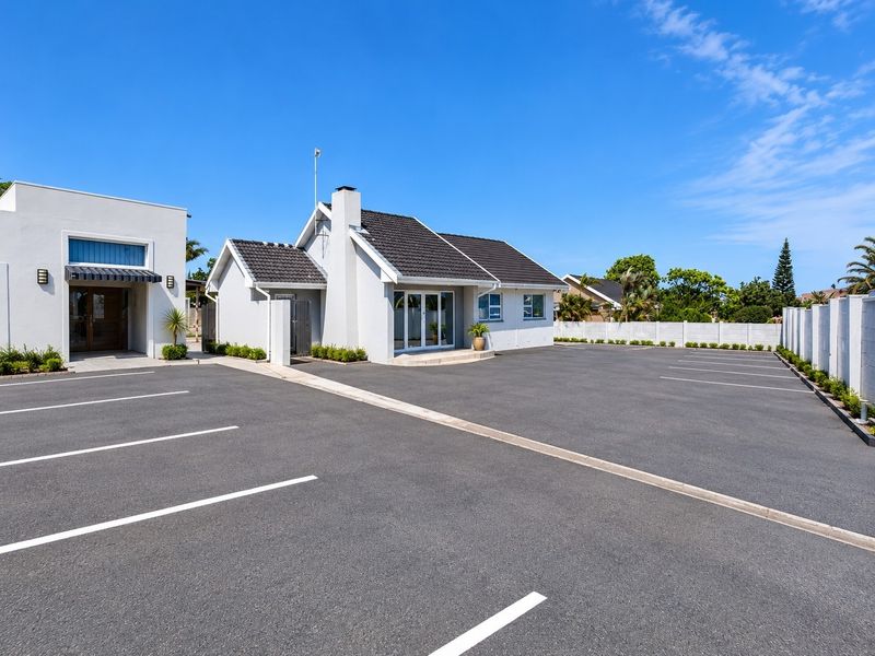 Commercial property exterior featuring a well-maintained asphalt parking area, modern white facade, and tiled roof structure.