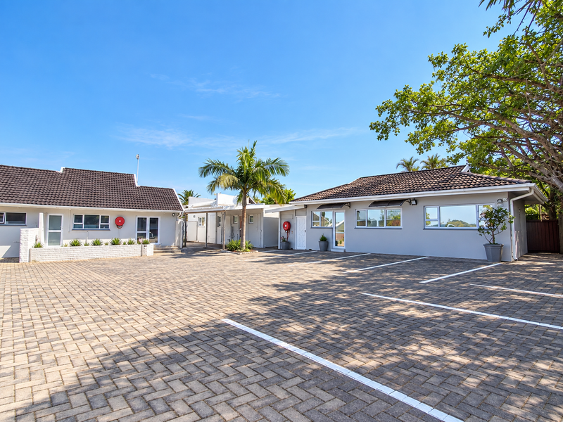 A well-maintained commercial property exterior featuring a paved parking area, tiled roofing, and modern painted masonry facades with fire safety equipment.