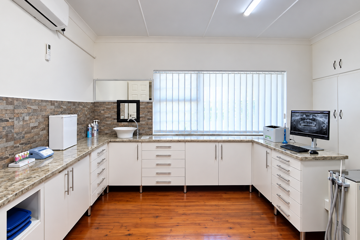 A well-maintained dental or medical office featuring extensive built-in cabinetry, stone-look countertops, a vessel sink, and polished timber flooring.