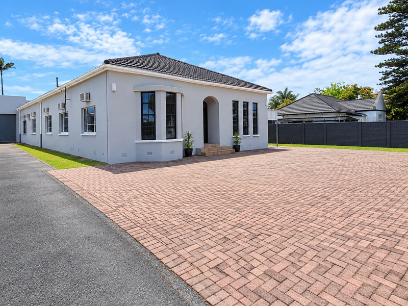 Front exterior view of the office property featuring a paved driveway, double garage, and well-maintained facade with multiple air conditioning units.