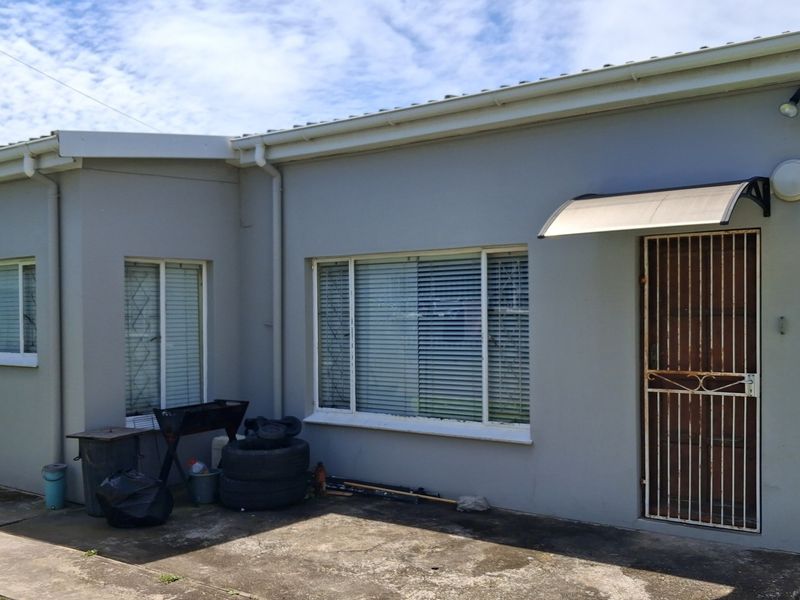 Rear exterior view of the office building featuring concrete paving, security gate, and external lighting fixtures.