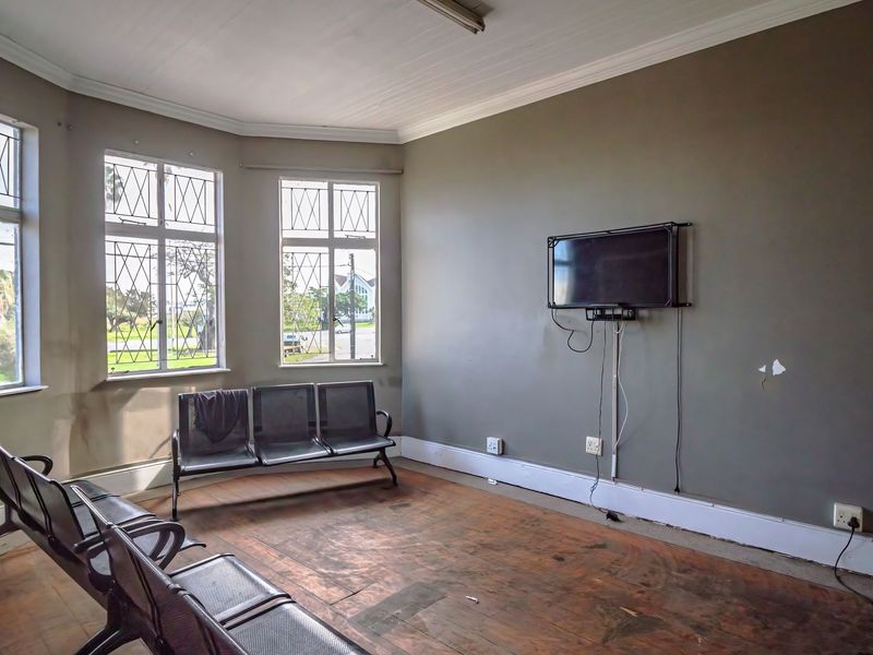 A commercial waiting area featuring timber flooring, leaded glass windows, and coved ceilings, currently showing signs of wear and requiring cosmetic updates.
