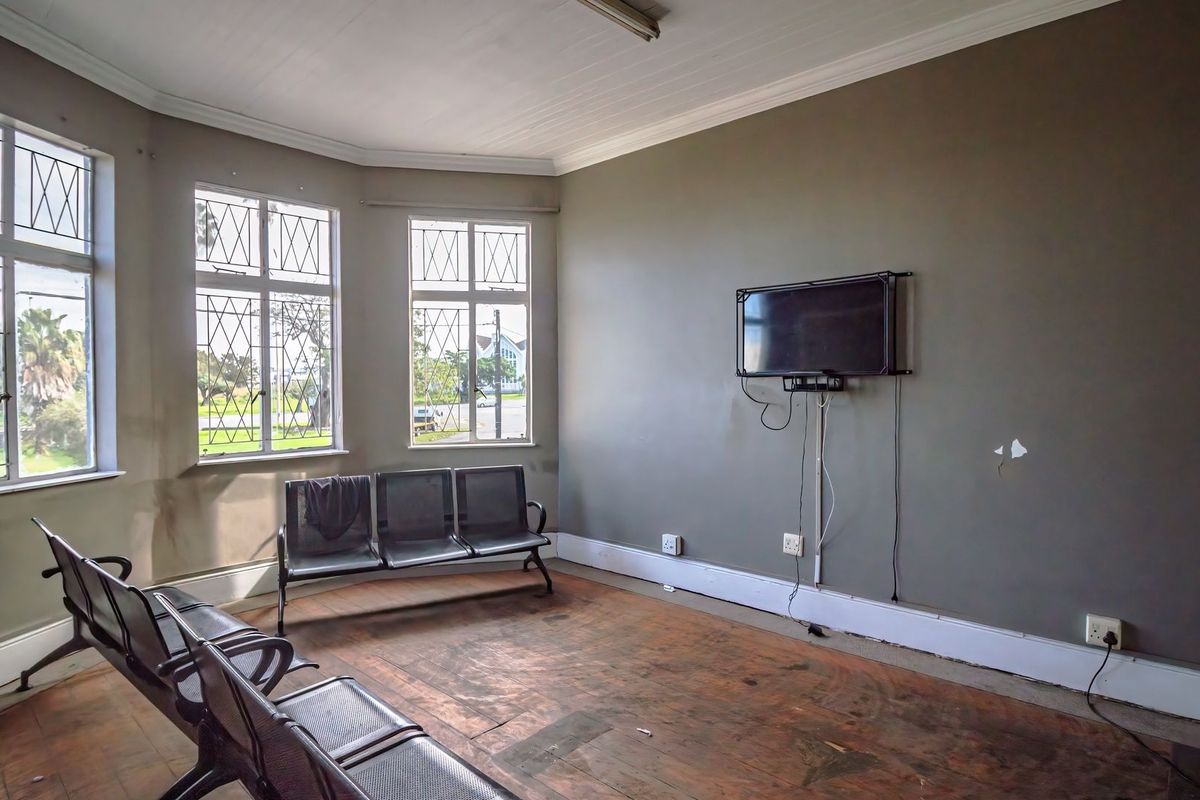A commercial waiting area featuring timber flooring, leaded glass windows, and coved ceilings, currently showing signs of wear and requiring cosmetic updates.
