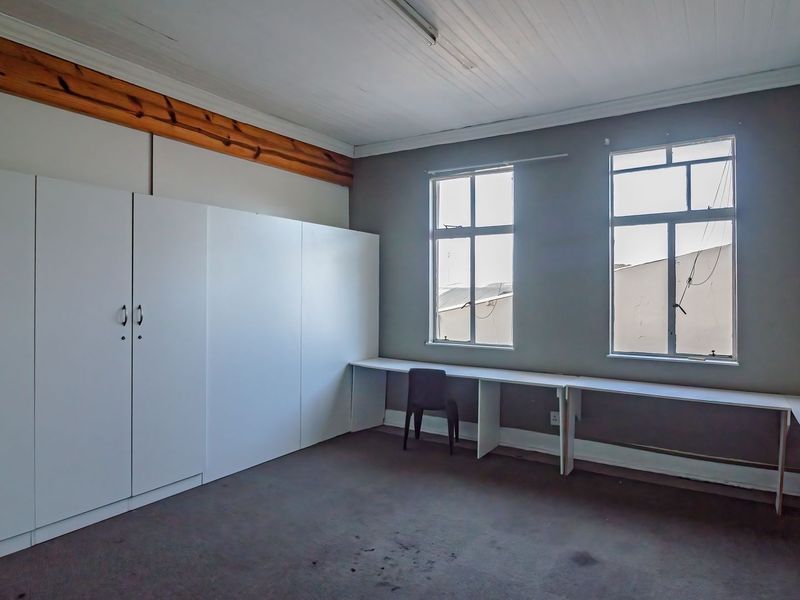 A functional office space featuring built-in cabinetry, a fitted desk area, and timber ceiling details, providing a practical workspace environment.