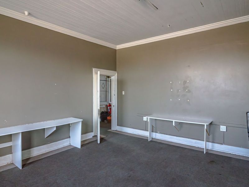A vacant office space featuring built-in desks, crown molding, and a tongue and groove ceiling, requiring minor cosmetic updates to the walls and flooring.