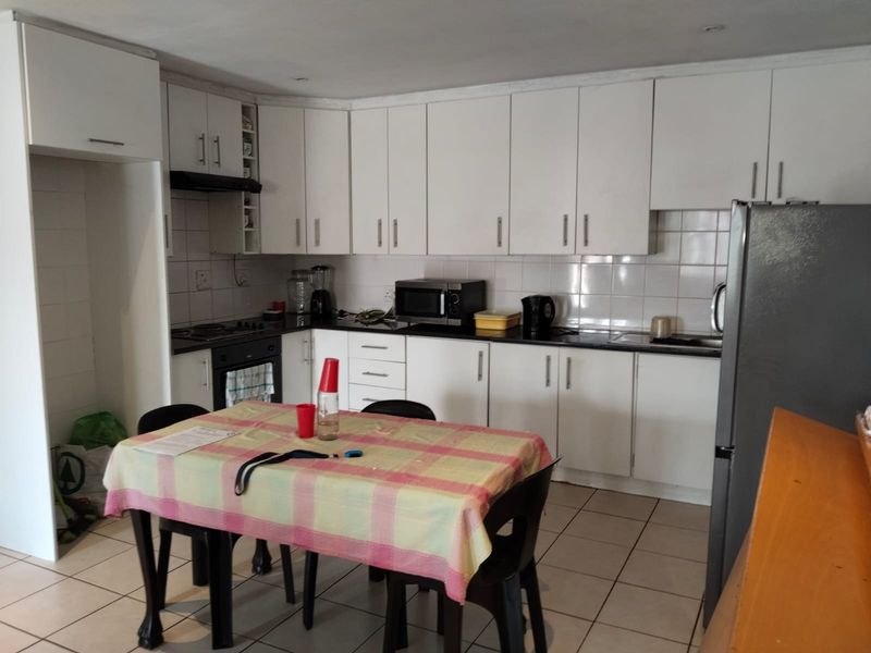 Functional kitchen featuring white cabinetry, tiled backsplash, built-in oven, hob, and ceramic floor tiles, offering a practical layout for daily meal preparation.