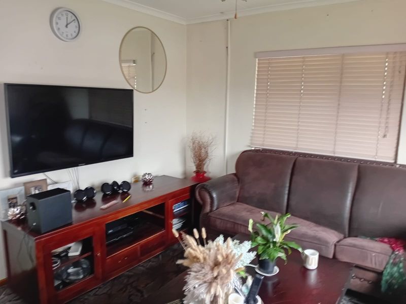 A comfortable living room featuring neutral walls, coving, and venetian blinds, providing a functional and well-lit space for relaxation.